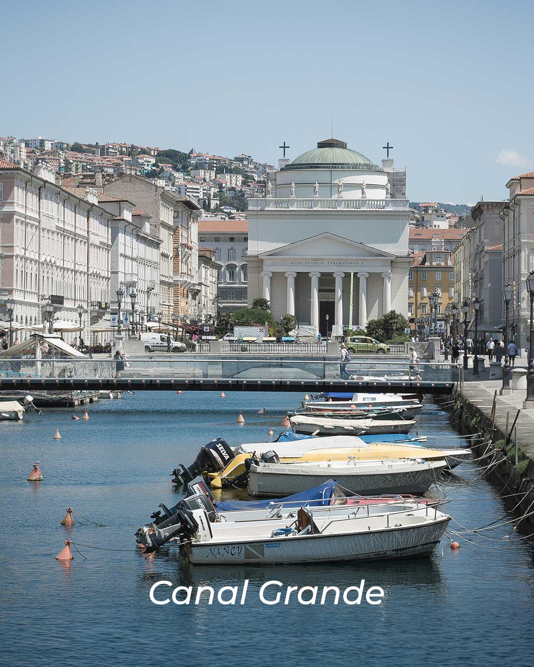 Boats docked along the Canal Grande in Trieste, with historic buildings lining the waterfront